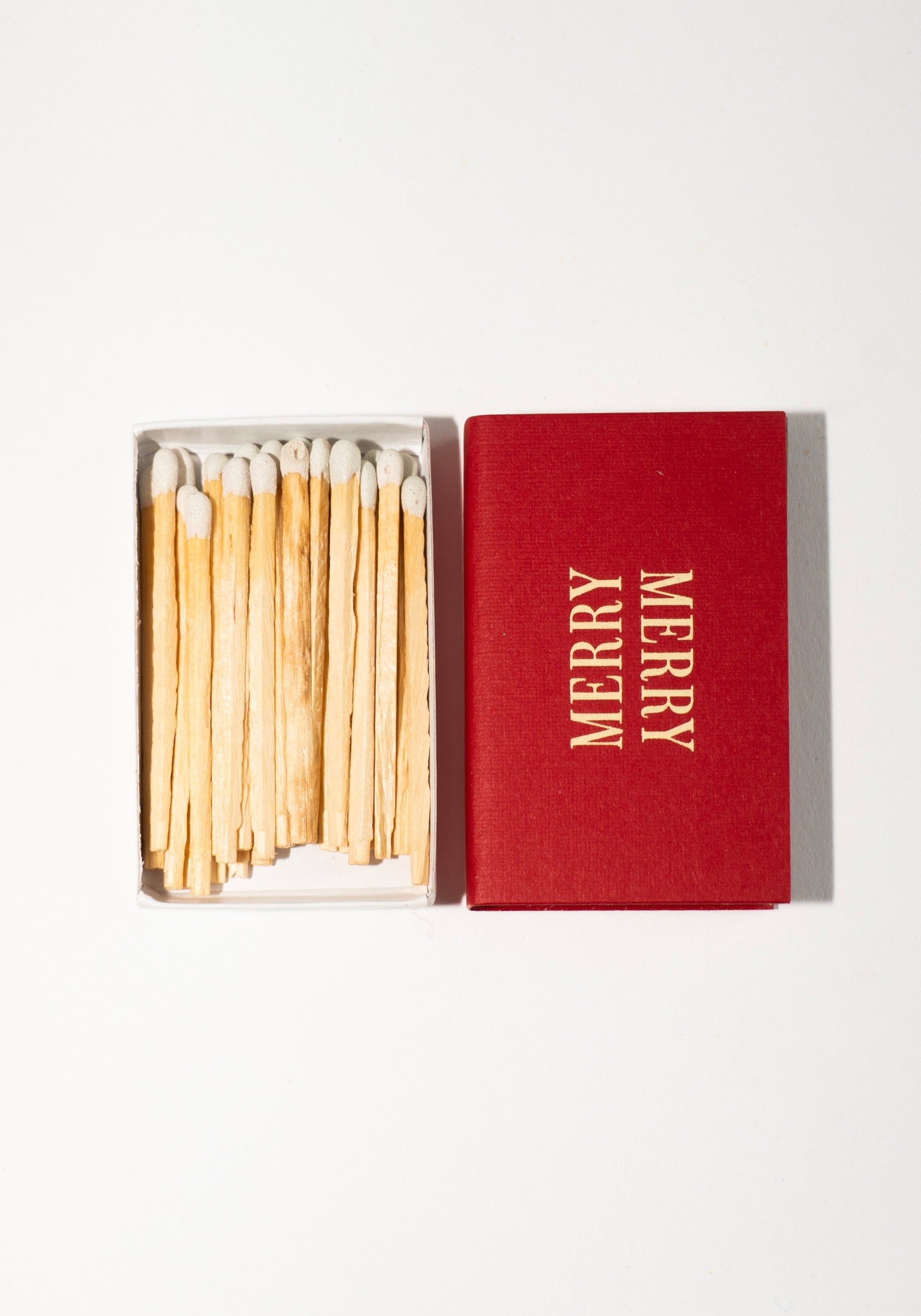 Red matchbox with 'Merry' text and matches on a white background
