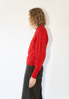 Person wearing a red sweater and dark pants on a white background