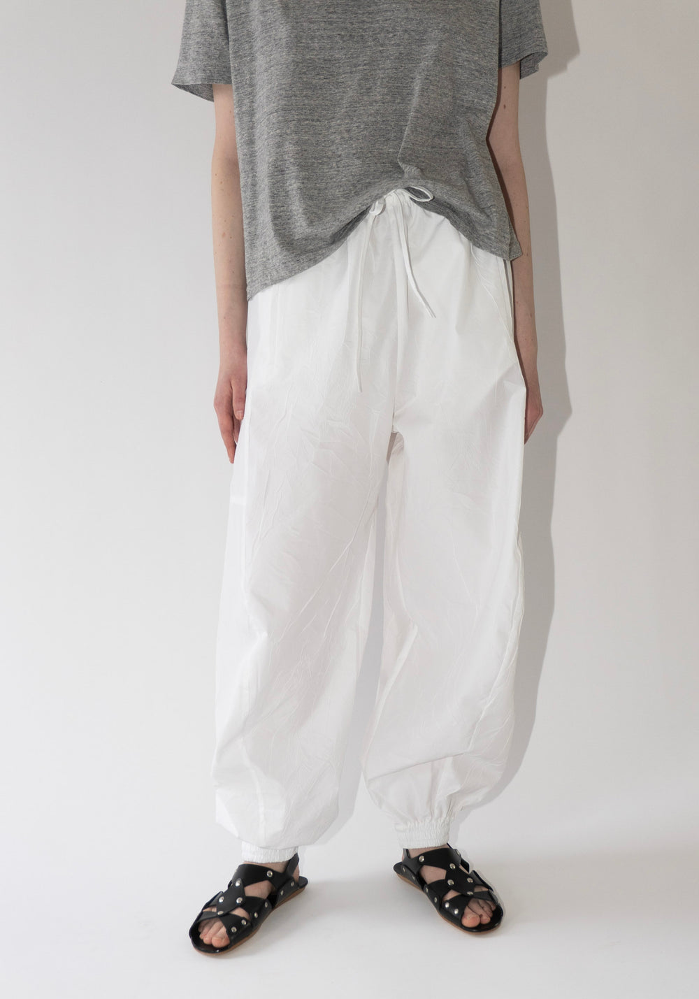 Volume Crushed Cotton Trousers in Optic White from Róhe. Elastic drawstring waist trouser with elasticated cuffs to create a softly rounded, voluminous leg silhouette.